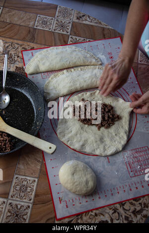 Close up of a woman's hands faire la pâte pour le pain maison, des empanadas. female baker la préparation de pain sur une plaque à pâtisserie en silicone poêle avec grinn. Banque D'Images