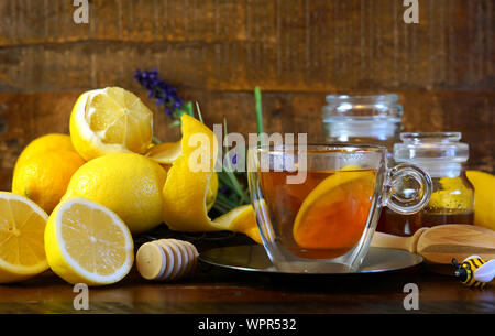 Citrons et miel traditionnel servi avec une tasse de thé sur fond de bois rustique. Banque D'Images