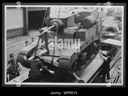 Un Américain M3A1 Stuart char léger, fournis par, prêt-bail est déchargée sur un réservoir transporteur, au port australien de Melbourne, Victoria, le 20 février 1943, pour utilisation par une division blindée. Légende américaine d'origine américaine : l'équipement prêt-bail joue un rôle vital dans le développement de l'Organisation des Nations Unies les forces mécanisées. Ici, un char léger, d'être utilisé pour la formation des équipages de blindés de l'Australie, est déchargé à un port australien. Australienne d'origine légende : Melbourne, VIC. 1943-02-20. Arrivée EN AUSTRALIE DE BAIL-prêter de matériaux provenant de l'Amérique. Le PERSONNEL D'UNE AUSTRALIE Banque D'Images