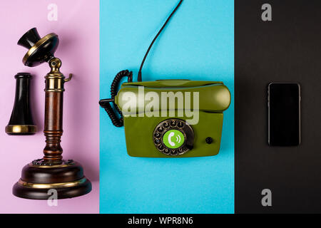 Vieux téléphone vintage marron avec un téléphone filaire téléphone mobile vert et sur les fonds de couleur différents. Le concept de développement de téléphone Banque D'Images