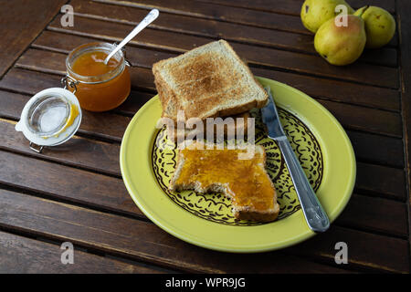 Petit-déjeuner rustique, des toasts avec de la confiture sur une table en bois d'époque, vieille plaque jaune et des fruits dans l'arrière-plan Banque D'Images