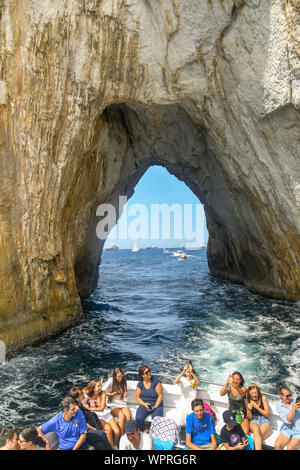 Île de Capri, ITALIE - AOÛT 2019 : les gens à l'arrière d'un bateau qui a traversé les faraglioni rock formation au large de la côte de Capri. Banque D'Images