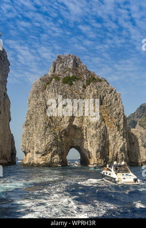 Île de Capri, ITALIE - AOÛT 2019 : Les Faraglioni rock formation au large de la côte de Capri. De petites embarcations sont en passant par l'arche. Banque D'Images