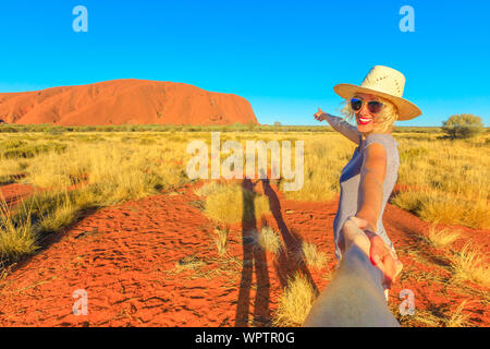 Suivez-moi, smiling girl with hat holding hands at Parc National d'Uluru-Kata Tjuta, Territoire du Nord, Australie. Concept de voyage de touriste Banque D'Images