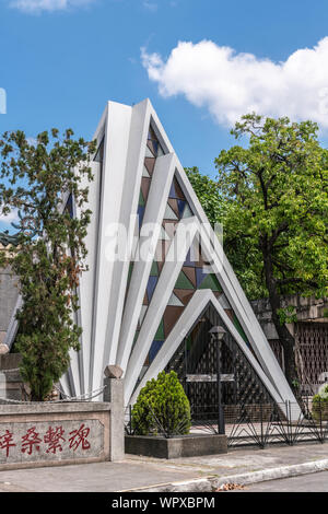 Manille, Philippines - 5 mars 2019 : cimetière chinois dans la partie de la ville de Santa Cruz. Chapelle comme une pyramide avec fenêtres en verre. Bleu ciel et vert Banque D'Images