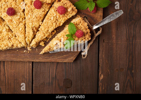 Fabricants de pièces triangulaires de tarte crumble aux pommes sur une planche de bois brun, vue du dessus Banque D'Images