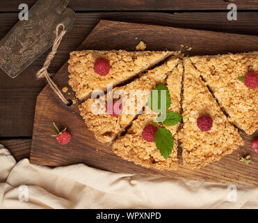 Fabricants de pièces triangulaires de tarte crumble aux pommes sur une planche de bois brun, vue du dessus Banque D'Images