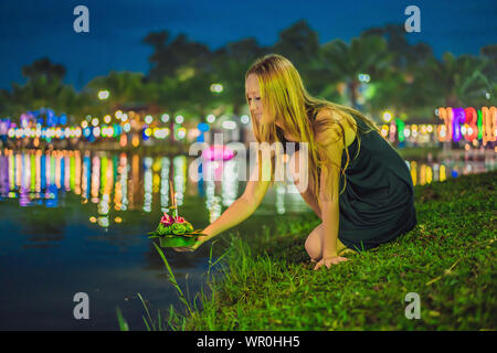 Une femme tient le tourisme Loy Krathong dans ses mains et s'apprête à lancer à l'eau. Loy Krathong festival, les gens achètent des fleurs et bougie pour Banque D'Images