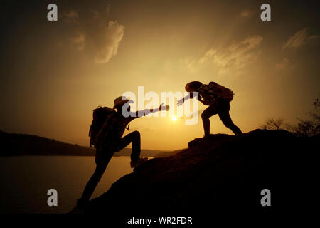 Backpacker donnant coup de main sur fond de montagne au coucher du soleil.Adventury concept Banque D'Images