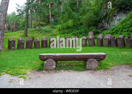 Un grand banc en bois fait de la moitié d'un tronc d'arbre sur une pelouse verte dans un parc Banque D'Images
