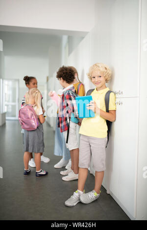 Garçon avec comprimé bleu, debout près de amis dans couloir d'école Banque D'Images