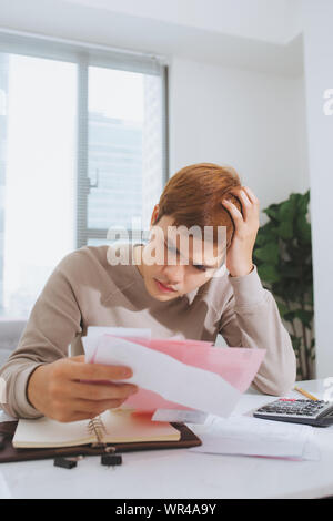 Jeune homme asiatique comptant à l'aide de la calculatrice et le stress en problème de dépenses. Banque D'Images