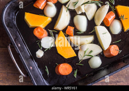 Cuire les légumes - Légumes crus dans un plat à four - top view photo de butternut, pomme de terre, oignon, carotte et ail pieses surmontée de l'ONU de romarin frais Banque D'Images