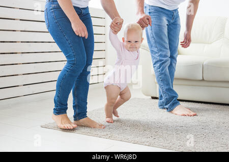 La famille, les enfants et la parentalité concept - enseignement parents baby girl de marcher. Banque D'Images