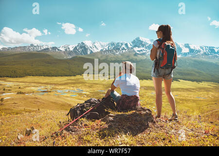 Deux randonneurs se détendre sur le dessus de colline et regarde les montagnes blanches Banque D'Images