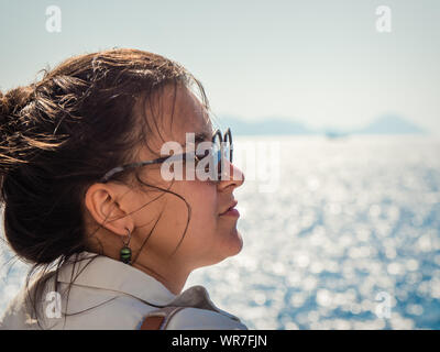 Jeune femme avec des lunettes de profiter de la brise marine sur un bateau en mer. Banque D'Images