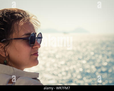 Jeune femme avec des lunettes de profiter de la brise marine sur un bateau en mer. Banque D'Images