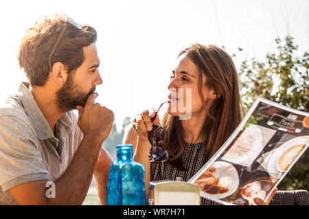 Heureux couple sitting at table bar extérieur à rome petit déjeuner menu lecture de décider si un cappuccino, café ou cornet Banque D'Images