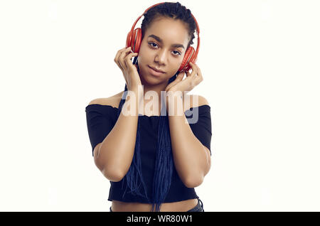 Portrait de l'Afrique belle brunette woman avec des dreadlocks à l'écoute de la musique via un casque sans fil isolé sur fond de studio Banque D'Images