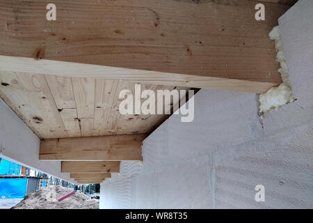 L'installation de poutres en bois de charpente avec spray foam sur le mur de la maison en construction. Banque D'Images