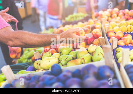 Close up of man cueillette à la main jusqu'à l'échoppe de marché en plein air de nectarine. Banque D'Images