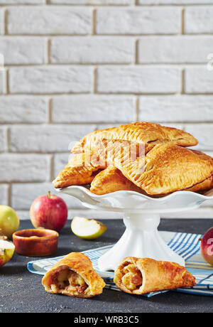 Le chiffre d'Apple sur un gâteau en porcelaine blanche se tient debout sur une table en béton foncé avec des pommes fraîches et un mur de brique à l'arrière-plan Banque D'Images