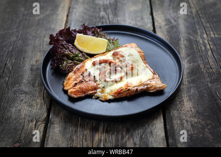 Le poisson cuit au four avec tomates séchées et fromage mozzarella. Banque D'Images