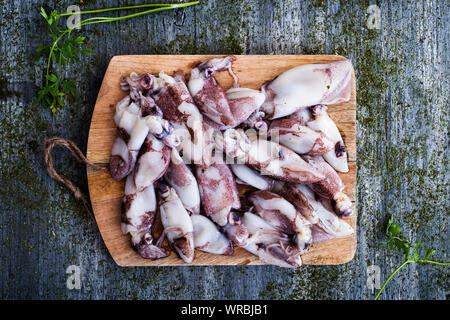 Portrait de certaines matières chipirones, espagnol petit calmars, sur une planche à découper en bois, placé sur une table en bois rustique gris, parsemé de differe Banque D'Images