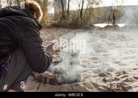 Man cooking barbecue sur la plage. Pique-nique sur la plage fluviale avec husky puppy. Banque D'Images