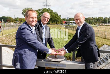 10 septembre 2019, Hambourg : Jens Kerstan (Bündnis90/Die Grünen, l-r), le sénateur de l'environnement de Hambourg, l'Olaf Müller, Directeur de la protection de l'eau dans l'entreprise d'état des routes, des ponts et des eaux (LSBG), et Michael Westhagemann (non partie), le sénateur pour le transport et l'économie, ouvrir la porte d'une usine de traitement biologique des eaux usées pour la route pour la mise en service. Il est destiné à de l'eau de pluie à partir d'un rayon de 40 hectares jusqu'à neuf tonnes de polluants par an, qui se composent principalement de microplastics de l'abrasion des pneus de voiture. Photo : Markus Scholz/dpa Banque D'Images