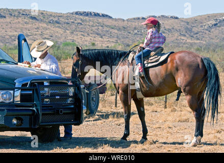 Jeune fille regardant son père, un ranch manager, tenant le bétail expédié après un résumé sur un ranch au Texas. Banque D'Images