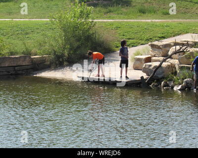 Deux garçons jouant avec un bâton le long de la rivière Concho à San Angelo, Texas, Etats-Unis Banque D'Images