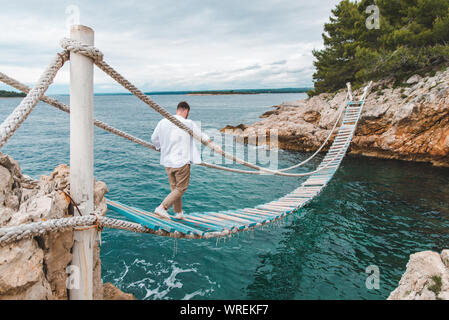 Homme marchant par suspension bridge Banque D'Images