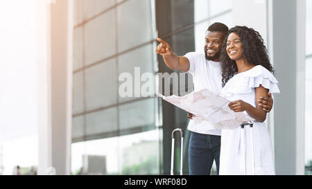 Happy black jeunes mariés à la recherche du site à l'aéroport, la planification de miel Banque D'Images