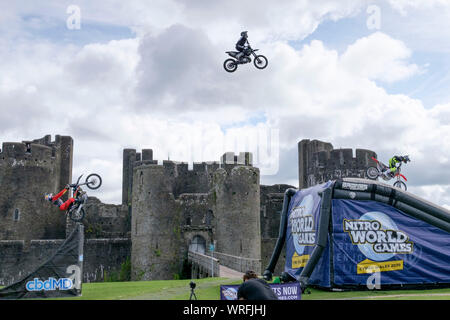 Caerphilly, Wales, UK. 10 septembre 2019. Trois Croix Moteur Freestyle (FMX) étoile effectuer le jamais vu avant "double backflip synchronisés train" devant tout aussi spectaculaire château de Caerphilly. Cascadeurs Jackson Strong, Josh Sheehan et Luc Ackerman, sont parmi les plus réussies FMX étoiles dans le monde. L'affichage fait la promotion de la prochaine 2020 Monde Nitro Jeux à être mis en scène dans la Principauté Stadium de Cardiff. Crédit : Mr Standfast/Alamy Live News Banque D'Images