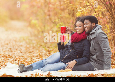 Pique-nique d'automne. Afro couple drinking hot coffee Banque D'Images