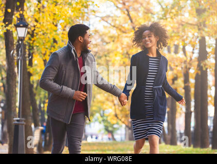 Happy black couple running sur golden park Banque D'Images