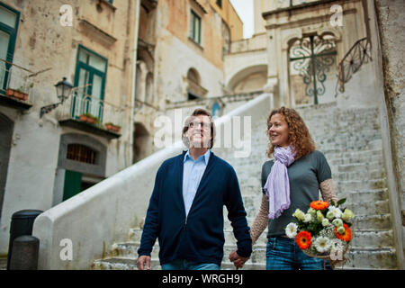 Smiling middle aged couple marche main dans la main en descendant une volée de marches en pierre. Banque D'Images