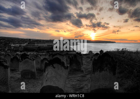 Coucher de soleil sur la côte de Whitby, avec St Marys dans l'avant-plan, North Yorkshire, England, UK Banque D'Images