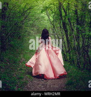 Sorcière de la rivière, assis sur un rocher dans la rivière. Robe rose, une image à la mode fabuleux.tonifiant. Couleur créative. Belle danseuse dans une forêt mystique b Banque D'Images