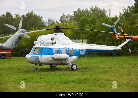 Petit hélicoptère blanc avec une bande bleue sur l'herbe verte. Banque D'Images