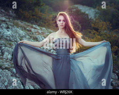 Portrait d'été dehors belle furieux guerrier scandinave ginger femme en robe grise avec métal chaîne mail. Haut dans la montagne, brouillard et mon Banque D'Images