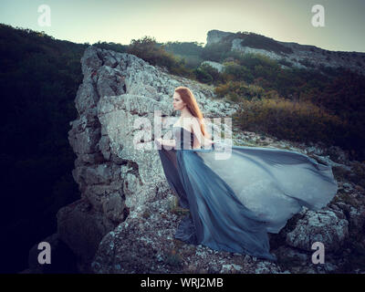 Portrait d'été dehors belle furieux guerrier scandinave ginger femme en robe grise avec métal chaîne mail. Haut dans la montagne, brouillard et mon Banque D'Images