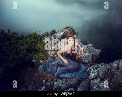 Portrait d'été dehors belle furieux guerrier scandinave ginger femme en robe grise avec métal chaîne mail. Haut dans la montagne, brouillard et mon Banque D'Images