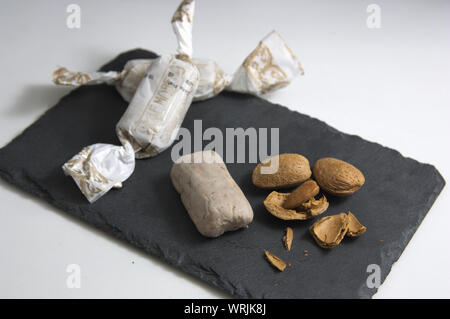 La plaque d'ardoise sur laquelle il y a des amandes brutes fraîchement coupé à côté de certains d'amande de Noël traditionnelles alfajores en Espagne Banque D'Images