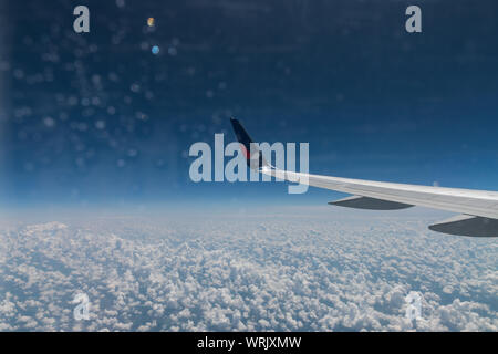 Ici, c'est vue depuis le hublot de l'avion sur l'aile de l'avion, le sol et les nuages d'une journée d'été en fuite. Billet d'avion, vol, jet, c Banque D'Images