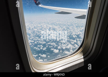 Ici, c'est vue depuis le hublot de l'avion sur l'aile de l'avion, le sol et les nuages d'une journée d'été en fuite. Billet d'avion, vol, jet, c Banque D'Images