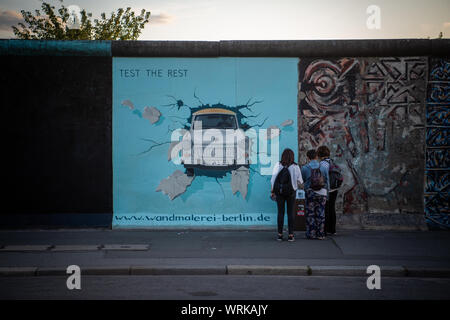 19 août 2019, Berlin : les visiteurs et les touristes sont devant le Trabi photo de l'artiste Birgit Kinder à l'East Side Gallery. Il y a près de 30 ans, les artistes eux-mêmes immortalisés ici et réinterprété la plus longue partie restante du mur de Berlin avec leurs œuvres d'art. Photo : Arne Immanuel Bänsch/dpa Banque D'Images