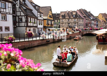 Un bateau à fond plat emmène les touristes vers le bas le canal en aval des maisons médiévales à pans de bois dans la petite Venise à Colmar, France. Banque D'Images