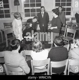 Années 1960, historiques, de théâtre amateur, les gens dans un groupe de théâtre à répéter une pièce de théâtre en salle des fêtes, suivi par les autres joueurs, England, UK. Banque D'Images